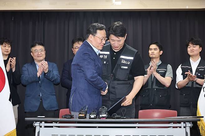 20일 경기도 수원시 장안구 경기고용노동청에서 여명구 삼성전자 DS(디바이스솔루션·반도체 사업 담당) 피플팀장과 최승호 삼성그룹 초기업노동조합 삼성전자지부 위원장이 잠정 합의안에 서명한 후 손을 맞잡고 있다. 연합뉴스