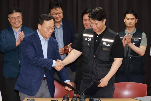 지난 20일 경기도 수원시 장안구 경기고용노동청에서 열린 삼성전자 임금협상을 마친 뒤 여명구 삼성전자 반도체(DS)부문 피플팀장과 최승호 삼성그룹 초기업노동조합 삼성전자지부 위원장이 잠정 합의안에 서명한 뒤 손을 맞잡고 있다. 공동취재사진