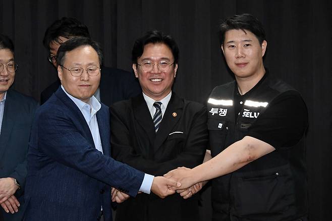 지난 20일 경기도 수원시 장안구 경기고용노동청에서 열린 삼성전자 임금협상을 마친 후 여명구 삼성전자 DS(디바이스솔루션·반도체 사업 담당) 피플팀장과 김영훈 고용노동부 장관, 최승호 삼성그룹 초기업노동조합 삼성전자지부 위원장이 잠정 합의안에 서명한 후 손을 맞잡고 있다. 공동취재단