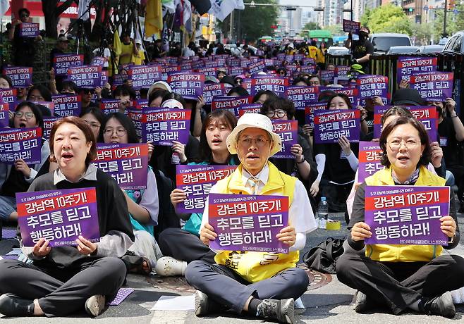 Participants chant slogans while holding placards reading “Gangnam Station, 10 years on: Turn mourning into action,” during a memorial rally held Sunday near Exit 10 of Gangnam Station in Seoul, marking 10 years since a woman was killed near the station. (Yohhap)