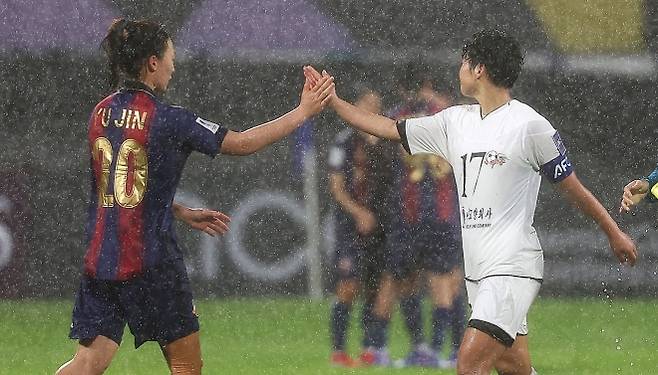 수원FC위민 수비수 이유진(왼쪽)과 북한 내고향여자축구단 주장 김경영이 20일 경기 수원종합운동장에서 2025~26 아시아축구연맹 여자 챔피언스리그 준결승전 우중 혈투를 벌인 직후 서로의 손뼉을 부딪치며 격려하고 있다. 경기는 내고향이 김경영의 역전 결승 골에 힘입어 수원을 2-1로 꺾었다. 연합뉴스