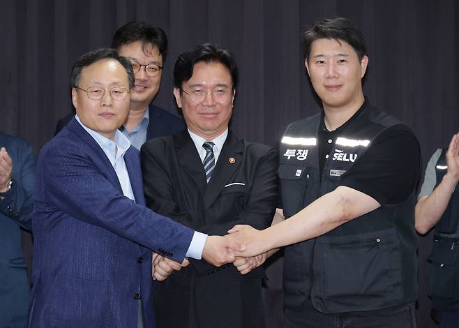 20일 경기도 수원시 장안구 경기고용노동청에서 열린 삼성전자 임금협상을 마친 후 여명구 삼성전자 반도체(DS)부문 피플팀장과 최승호 삼성그룹 초기업노동조합 삼성전자지부 위원장이 잠정 합의안에 서명한 후 김영환 고용노동부 장관과 손을 맞잡고 있다. 연합뉴스