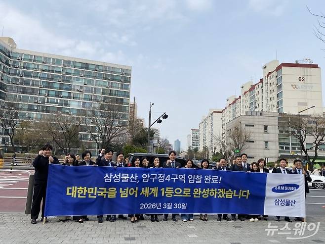 삼성물산 관계자들이 지난 3월 30일 압구정4구역 앞에서 현수막을 들고 사진을 찍고있다. 사진=이재성 기자