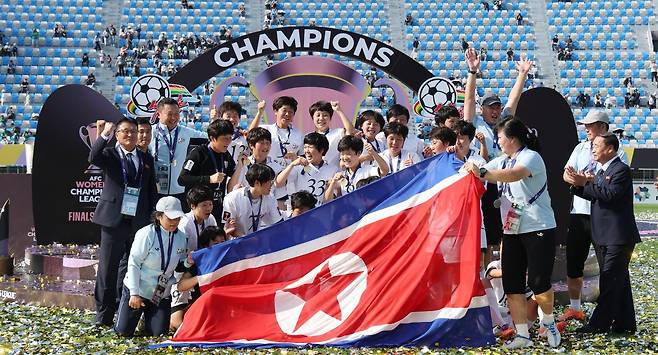 북한 내고향여자축구단 선수들이 23일 경기 수원시 수원종합운동장에서 아시아축구연맹(AFC) 여자 챔피언스리그 우승을 거둔 뒤 인공기를 펼친 채 기념 촬영을 하고 있다. 수원=뉴스1