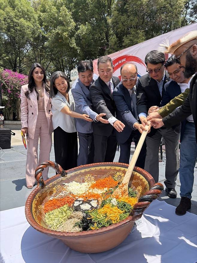 거대 비빔밥을 비벼라. (멕시코시티=연합뉴스) 송광호 특파원 = 12일 멕시코시티에서 열린 '월드컵 성공 및 한반도 평화기원 평화통일 비빔밥 행사'에 참가한 참가자들이 비빔밥을 비비고 있다.2026.05.23. buff27@yna.co.kr