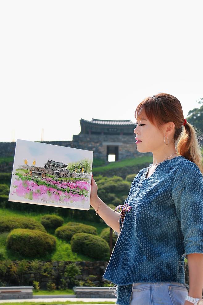 갬영주 작가가 충남 공주의 공산성 아래에서 자신의 작품을 들어 보이고 있다. 김영주 작가 제공
