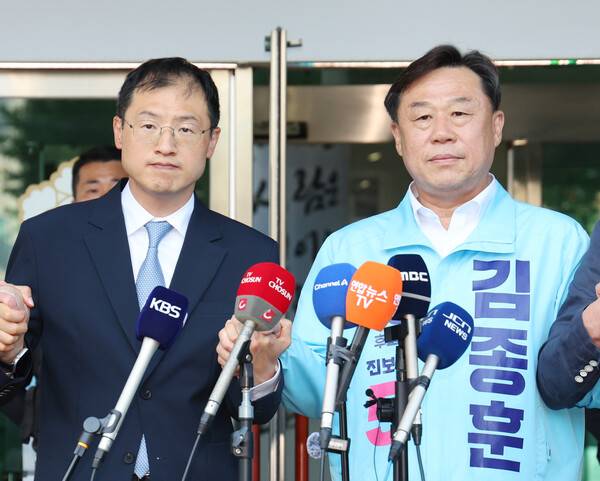 울산시장 선거에 출마한 민주당 김상욱 후보(사진 왼쪽)와 진보당 김종훈 후보가 사전투표 시작을 하루 앞둔 28일 범여권 후보단일화에 성공한 뒤 손을 맞잡으며 포즈를 취하고 있다. 2026.5.28 연합뉴스