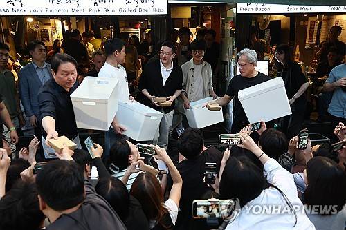 '시민들에게 선물'(서울=연합뉴스) 윤동진 기자 =젠슨 황 엔비디아 최고경영자(CEO)가 5일 서울 마포구 홍대 인근 삼겹살 음식점 '형님 저요'에서 최태원 SK그룹 회장, 구광모 LG그룹 회장, 이해진 네이버 의장과 '삼소(삼겹살·소주) 회동'을 하며 도넛이 담긴 도시락 상자를 시민들에게 나눠주고 있다. 2026.6.5 mon@yna.co.kr