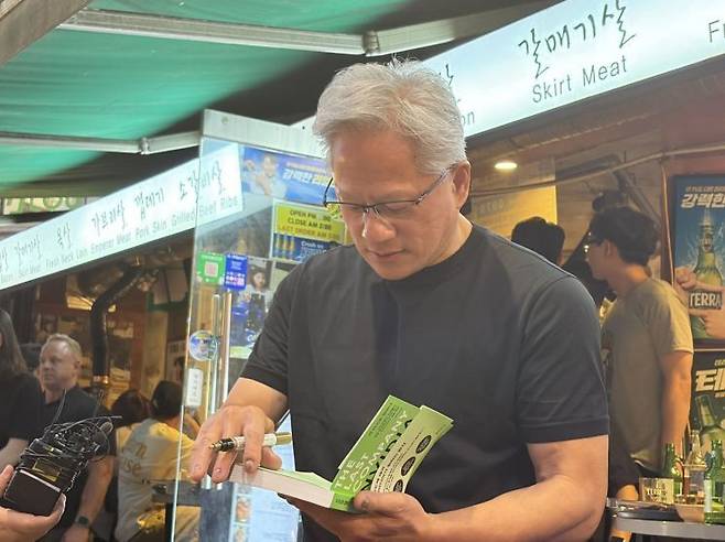 젠슨 황 엔비디아 최고경영자(CEO)가 5일 시민이 건넨 책에 서명을 하고 있다. 장보경 기자