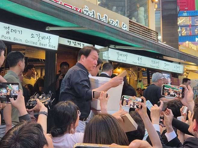 최태원 SK그룹 회장이 5일 '삼소 회동'을 위해 찾은 홍대 인근의 한 삼겹살 음식점에서 시민들에게 선물을 나눠주고 있다. ⓒ데일리안 정진주 기자