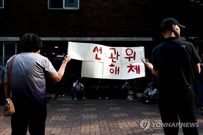 '선관위 해체' 손팻말 든 시민들 (서울=연합뉴스) 김성민 기자 = 4일 제9회 전국동시지방선거 및 국회의원 재·보궐선거 투표용지 부족으로 투표 시간이 오후 10시까지 연장됐던 서울 송파구 잠실7동 제2투표소 앞에서 투표함 반출에 반대하는 시민들이 손팻말을 들고 있다. 2026.6.4 ksm7976@yna.co.kr