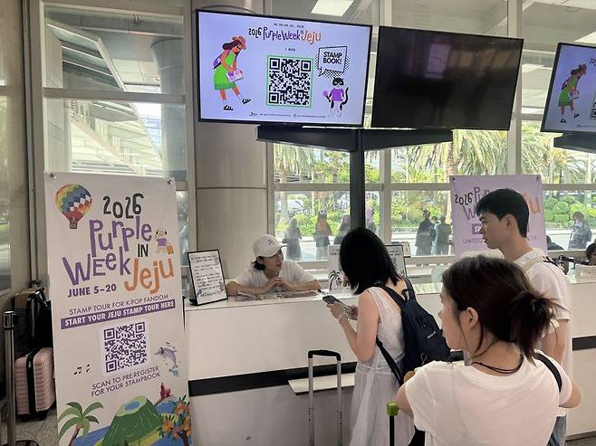 외국인 관광객들이 제주국제공항 1층 도착장에서 ‘2026 Purple Week in Jeju’ 스탬프북을 수령하고 있다. 제주관광공사는 오는 20일까지 제주 전역 31개 한류 관광지를 연결한 스탬프투어와 로컬문화 체험 프로그램을 운영한다. /사진=제주관광공사 제공