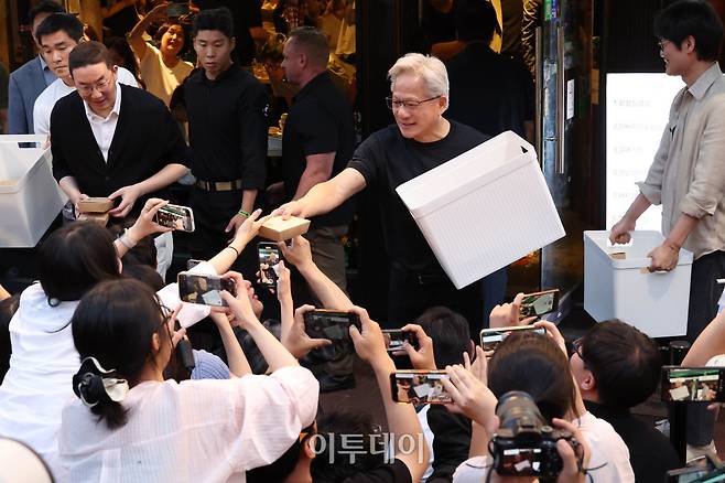 젠슨 황 엔비디아 최고경영자(CEO)가 5일 서울 마포구 홍대 인근 삼겹살 음식점 '형님 저요'에서 최태원 SK그룹 회장, 구광모 LG그룹 회장, 이해진 네이버 의장과 함께 '삼소(삼겹살·소주) 회동’ 중 취재진에게 간식을 나눠주고 있다. 고이란 기자 photoeran@