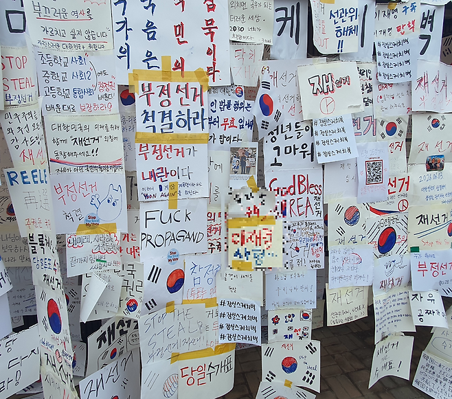 시위 참가자들이 직접 스케치북에 작성한 재선거 요구 손팻말들이 경기장 인근에 빼곡히 붙어 있다. 사진=최승한 기자