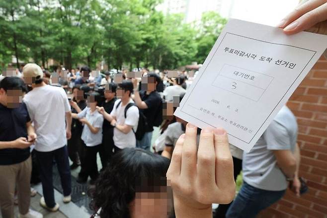 6·3 지방선거 본투표일인 지난 3일 서울 송파구 잠실2동6투표소에서 투표용지 부족으로 유권자들이 대기하는 등 혼란이 빚어지고 있다. 한 시민이 투표 마감시간 이후 투표가 순서대로 가능하도록 정한 대기표를 보여주고 있다. 연합뉴스
