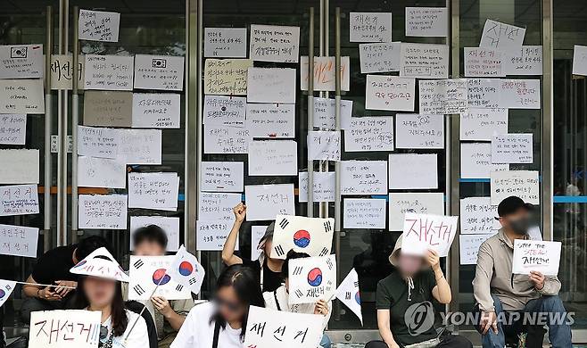 계속되는 '재선거' 외침 (서울=연합뉴스) 김인철 기자 = 6·3 지방선거 투표지 부족 사태를 규탄하며 재선거를 요구하는 '잠실 개표소 봉쇄 시위'가 계속되고 있는 7일 서울 송파구 올림픽공원 핸드볼경기장 출입구에 재선거를 요구하는 문구 등이 적힌 종이가 붙어있다. 2026.6.7 yatoya@yna.co.kr