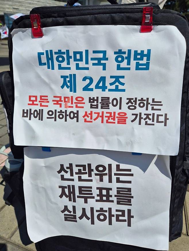 재투표를 촉구하는 문구가 붙어 있는 유권자의 가방. 사진=김예지 기자