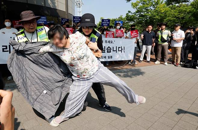 11일 서울 올림픽공원 핸드볼경기장 입주 체육단체 직원들이 경기장 앞에서 업무 정상화 호소문을 발표하고 있는 도중 한 남성 시위자가 난입해 난동을 벌이고 있다. 뉴시스
