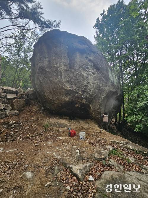불암산 계곡의 두꺼비바위에 새겨진 낙서를 공사업체 직원들이 제거하고 있다. 이 바위는 과거 굿당과 기도처로 이용되며 향과 촛불 연기에 검게 그을렸던 곳이다. 2026.6.11 남양주/이종우기자 ljw@kyeongin.com