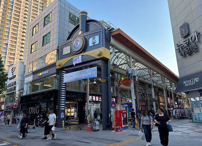 울산시민들이 지난 13일 오후 울산 시계탑 부근 증기 기관차 모양의 쇼핑거리에서 나와 울산 중구 옥교통 중앙전통시장으로 향하고 있다. 기관차 모양의 입구 오른쪽 아래 경동선 울산역 기념석이 세워져있다. 사진=최수상 기자