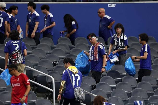 일본 축구팬들이 15일(한국시각) 미국 텍사스주 댈러스 스타디움에서 열린 2026 북중미월드컵 조별리그 F조 1차전 일본과 네덜란드의 경기가 끝난 뒤 관중석에서 쓰레기를 치우고 있다. 댈러스/AFP 연합뉴스