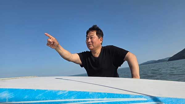 여수에서 출발해 다섯 개의 해상연륙교를 지나와 배를 타고 5분 남짓 가야 도착하는 태양의 섬에서 진 회장이 섬을 방문한 투자자들과 보트를 타고 섬을 돌며 섬의 특성에 대해 설명하고 있다.