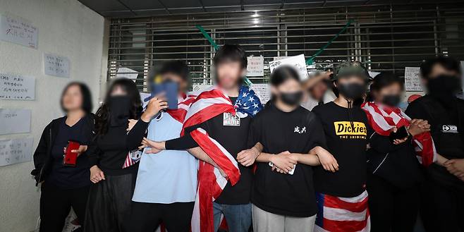 성조기 두르고 팔짱 꽉 6·3 지방선거 투표용지 부족 사태에 항의하며 개표소로 사용됐던 서울 송파구 올림픽공원 핸드볼경기장 봉쇄 시위를 하고 있는 시민들이 2일 ‘제9회 전국동시지방선거 투표용지 부족 사태 등 국민 참정권 침해 진상규명 및 선거관리 개혁을 위한 국정조사특별위원회’ 현장 조사를 막기 위해 출입문 앞에서 서로 팔짱을 끼고 서 있다. 연합뉴스