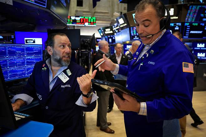 지난달 24일(현지 시간) 미국 맨해튼 뉴욕증권거래소(NYSE)의 거래중개인들이 증시 화면을 보며 대화하고 있다. 로이터연합뉴스