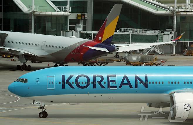 지난 5월 인천국제공항 제2터미널 계류장에서 대한항공(아래)과 아시아나항공(위) 여객기가 이동하는 모습. 2026.5.18 ⓒ 뉴스1 김진환 기자