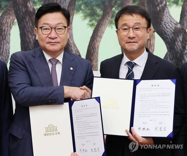 한병도 더불어민주당 대표 직무대행 겸 원내대표(오른쪽)와 정점식 국민의힘 원내대표가 21일 국회 운영위원장실에서 선관위 투표용지 부족 사태에 따른 특검법안 합의문에 서명한 뒤 악수하며 기념촬영을 하고 있다. 연합뉴스
