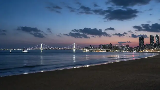 광안대교 조명이 물빛에 비치는 8월 저녁 해변