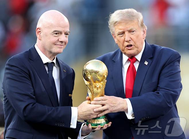 도널드 트럼프 미국 대통령과 잔니 인판티노 국제축구연맹(FIFA·피파) 회장이 지난 19일(현지시간) 미국 뉴저지주 이스트러더퍼드의 뉴욕 뉴저지 스타디움에서 열린 2026 FIFA 월드컵 스페인과 아르헨티나의 결승전 경기 직후 열린 시상식에서 스페인팀 주장 로드리에게 전달하기 전 월드컵 우승 트로피를 들어 올리고 있다. 2026.07.19. ⓒ AFP=뉴스1