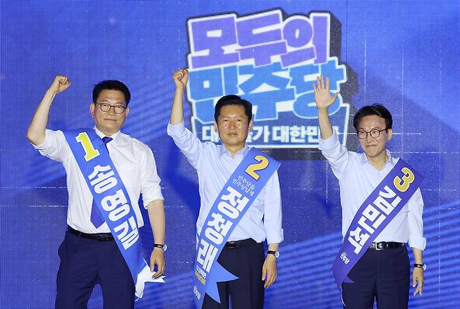 더불어민주당 당대표 후보인 송영길, 정청래, 김민석(왼쪽부터) 후보가 2일 부산 벡스코에서 열린 민주당 당대표·최고위원 순회경선 합동연설회에서 손을 들어 보이고 있다. 연합뉴스