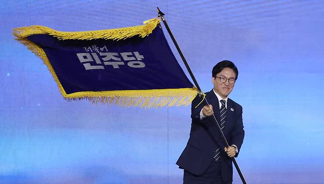 더불어민주당 당 대표에 출마한 김민석 전 총리가 17일 대전 컨벤션센터에서 열린 제3회 더불어민주당 정기 전국당원대회에서 당 대표 당선을 확정한 뒤 당기를 흔들고 있다. 연합뉴스