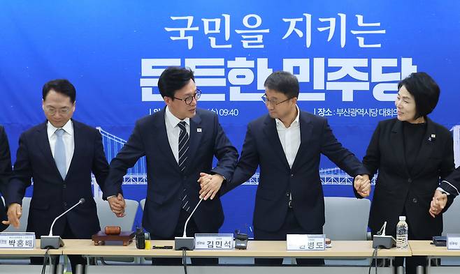 김민석 더불어민주당 대표가 19일 부산 동구 민주당 부산시당에서 열린 현장 최고위원회의에서 한병도 원내대표, 최고위원들의 손을 잡고 있다. /뉴스1