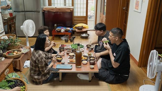 PM Kenobi와 뭐랭하맨이 제주 오합주 장인 김태자 어르신 댁을 찾아 제주 집밥을 함께하고 있다. (제주관광공사 제공)