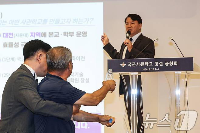 26일 오후 서울 용산구 국방컨벤션에서 열린 국군사관학교 창설 공청회에서 한 참석자가 발언하고 있는 김홍철 국방부 정책실장에게 생수병을 든 채 다가서고 있다. (공동취재) 2026.8.26 ⓒ 뉴스1 최지환 기자