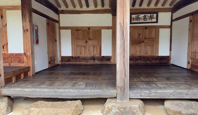 Weathered pillars and wooden floors, along with stones that have supported the house WOO JI-WON