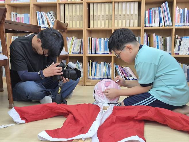 성승건 사진기자가 허수아비 얼굴에 눈코입을 그리고 있는 학생을 근접 촬영하고 있다. /김성후 선임기자