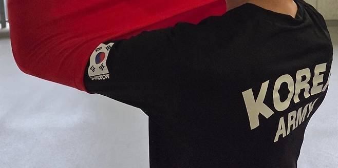 21일 한국과 북한의 아이치 나고야 아시안게임 여자 축구 경기에서 북한을 응원하던 조총련 관계자가 태극기가 붙은 티셔츠를 보여주고 있다. 등 뒤에 'KOREA ARMY'라고 써 있는 일명 '로카 티'였다. /이태동 기자