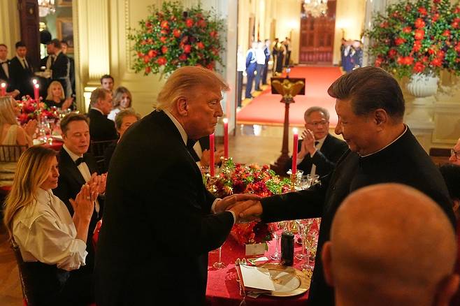 도널드 트럼프 미국 대통령이 24일(현지시간) 백악관에 열린 시진핑 중국 국가주석을 위한 국빈만찬에서 시 주석과 악수를 나누고 있다. 이날 만찬장엔 중국을 상징하는 붉은색 장식이 눈에 띄었고, 미국의 식재료로 요리한 중국식 음식이 다수 준비됐다. AP=연합뉴스