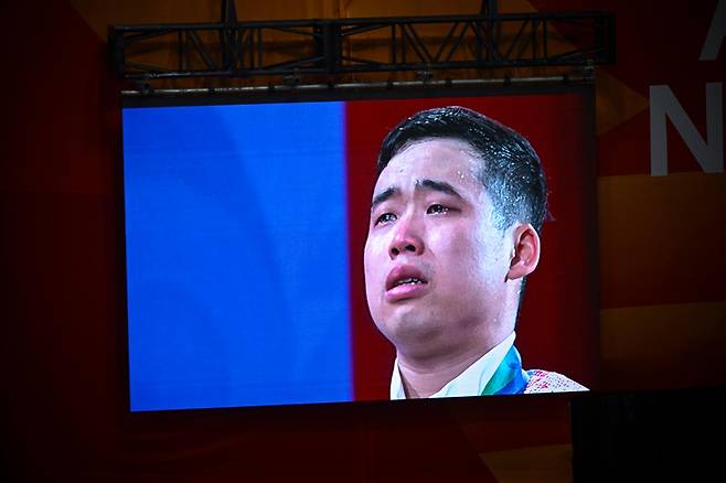 북한 로광렬이 28일 일본 나고야시 중소기업진흥회관에서 열린 2026 아이치·나고야 아시안게임 역도 남자 85㎏급 시상식에서 금메달을 목에 걸고 눈물을 흘리고 있다. 로광렬은 용상 214㎏, 합계 379㎏의 세계신기록으로 우승했다. 나고야=하상윤 기자
