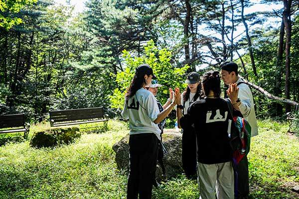'팔공산 개운산행' 참가자들이 눈을 감고 손을 맞대며 서로의 기운을 나누고 있다. 두 나무의 가지가 서로 맞닿은 '연리지'를 형상화한 프로그램이다.