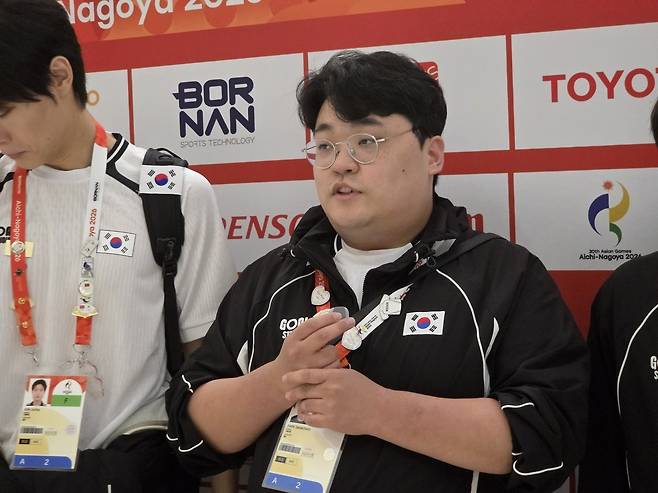 e스포츠 배틀그라운드 모바일 국가대표팀 ‘파비안’ 박상철이 28일 2026 아이치·나고야 아시안게임 1일 차 경기를 마친 뒤 믹스트존에서 취재진과 만나 인터뷰를 진행하고 있다. LoL 선수들과 마찬가지로 후원사 로고가 없는 유니폼을 입고 있다.