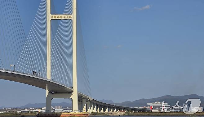 정식 개통을 하루 앞둔 14일 중국 랴오닝성 단둥에서 바라본 신압록강대교. 다리 위에 국기가 내걸려 있으며, 사진 오른쪽 북한 측 관문 기기둥부에 중국 오성홍기와 북한 인공기가 나란히 걸려 있다. 2026.10.14. ⓒ 단둥=뉴스1 노민호 특파원