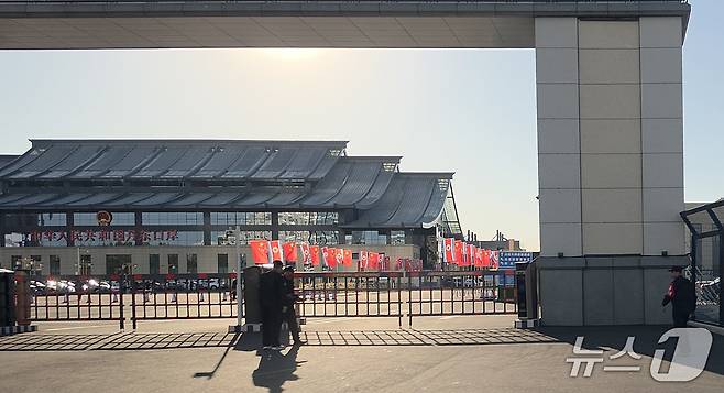 신압록강대교 정식 개통을 하루 앞둔 14일 중국 랴오닝성 단둥의 중국 측 해관(세관) 입구에서 공안들이 경비를 서고 있다. 시설 안에는 오성홍기와 인공기가 나란히 내걸려 있고, 인근에는 여러 차량이 주차돼 있다. 2026.10.14. ⓒ 뉴스1 노민호 특파원