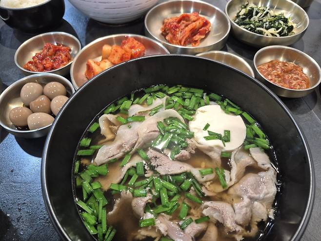 서울 강북구 삼양동 ‘차가돈’의 국밥. 맑은 갈색 국물에 얇게 썬 돼지고기가 넉넉하게 들어 있다. 부추와 순두부를 곁들였으며, 다양한 밑반찬이 함께 나온다.
