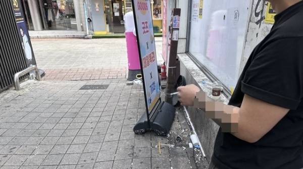 26일 청주 성안길 '금연선도거리' 옆 골목 바닥에 담배꽁초가 수북하게 쌓여 있는 가운데 한 시민이 흡연을 하고 있다. /조은영 기자