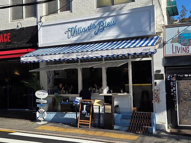 ▲빌라드블루 전경. 가게 왼쪽에 '레스토랑·바·비스트로' 화살표 표지판 아래 코카콜라 구명튜브를 단 이정표가 있다. 사진=송민규 기자